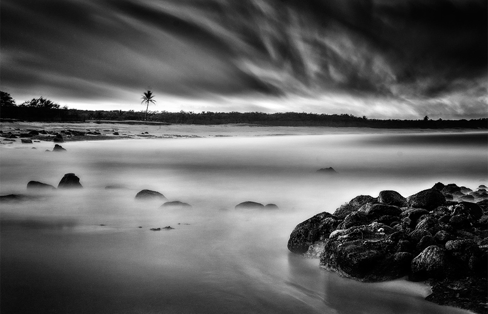 landscape photo of the beach with rocks and rolling clouds