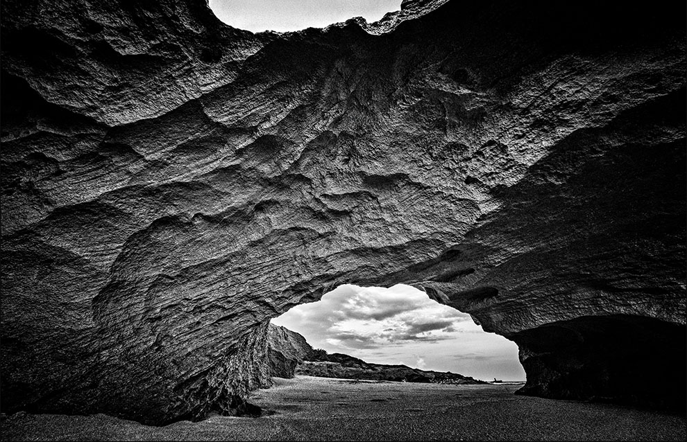 wide shot of a rock formation with an arch that allows for passage