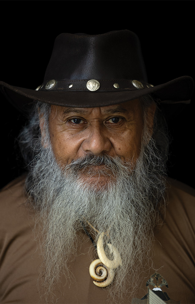closeup of a person with a long gray beard and mustache, wearing a black hat