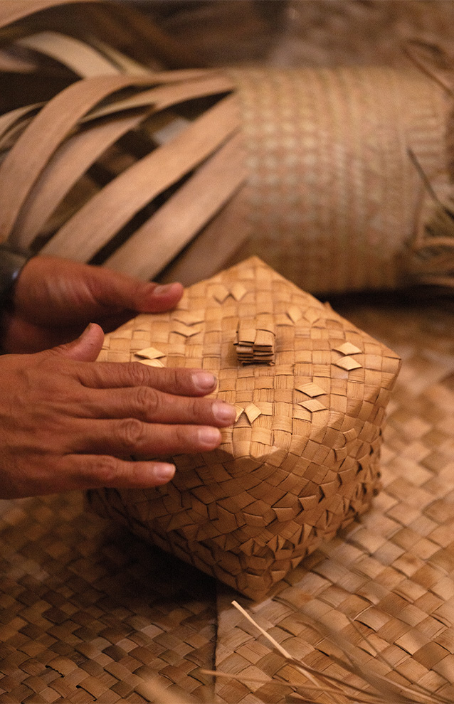 a closeip of a person holding a box made out of bamboo weaving