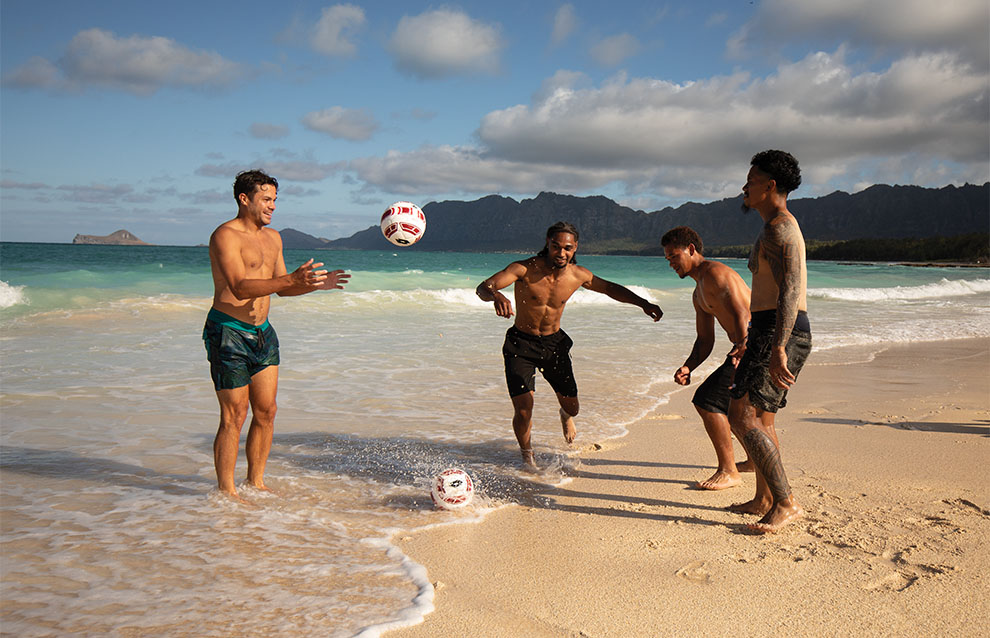 people at the beach playing football