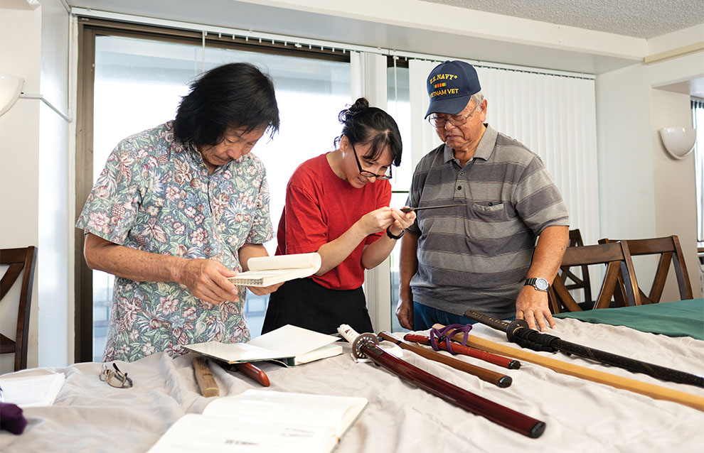 people gathered around, studying a sword